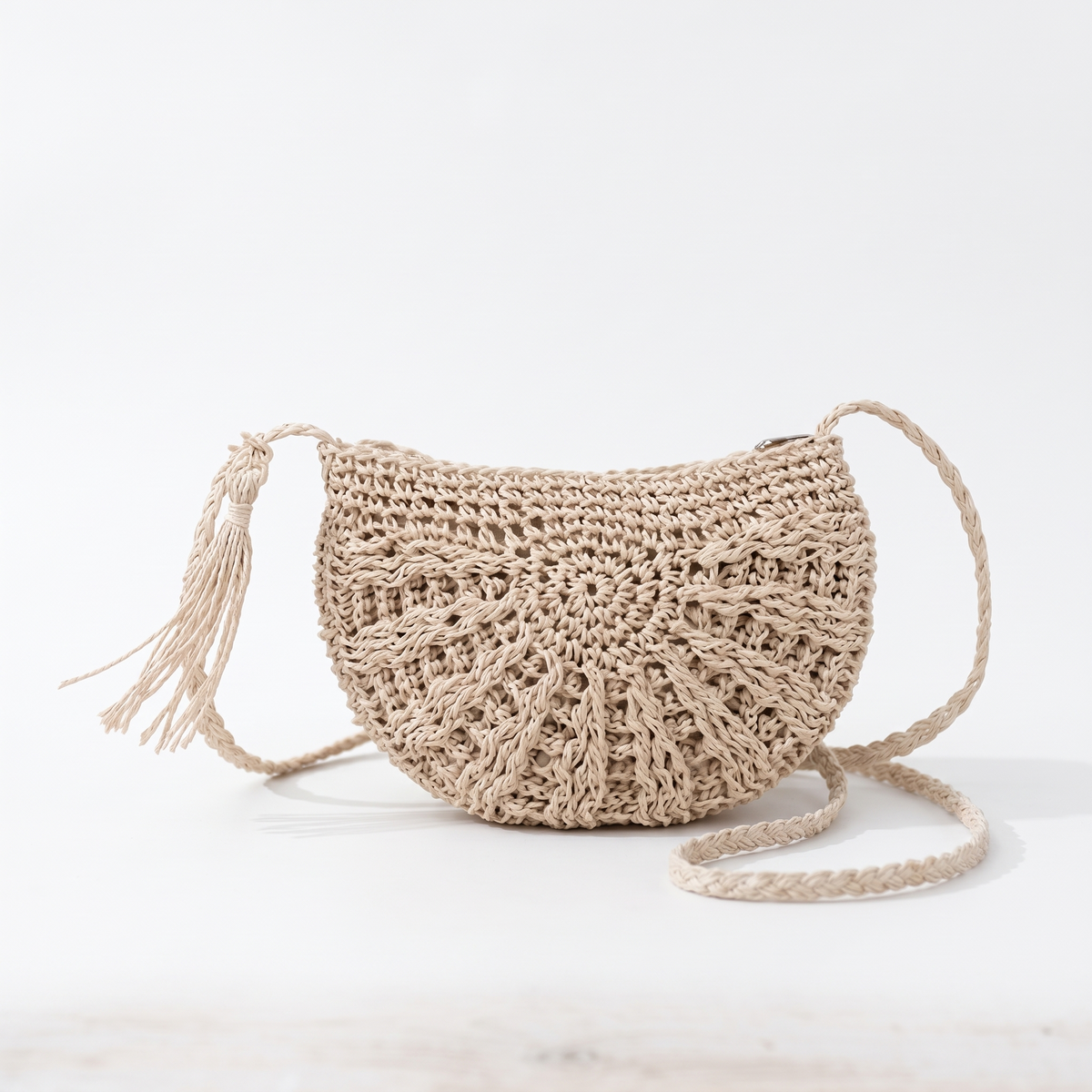 Sac bandoulière demi-lune en rotin ajouré sur fond blanc